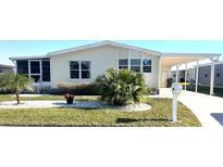 Mobile home with carport, landscaped yard, and screened porch at 563 Portside Dr, North Port, FL 34287