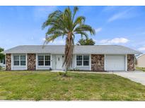 One-story home with gray exterior, stone accents, and palm tree at 6232 Drucker Cir, Port Charlotte, FL 33981