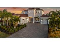 Two-story house with gray walls, tile roof, and a three-car garage at 7484 Ripetta St, Sarasota, FL 34240