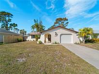 Charming single-story home with a well-manicured lawn, attached garage, and classic architectural details at 1023 Hope St, Venice, FL 34285