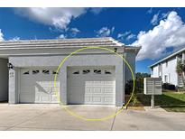 Two-car garage with white doors on a sunny day at 1041 Capri Isles Blvd # 119, Venice, FL 34292