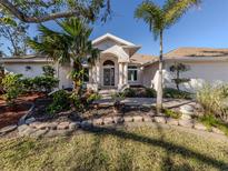 Charming single-story home with lush landscaping, mature trees, and a welcoming front entrance at 1093 Laurel Woods Dr, Nokomis, FL 34275