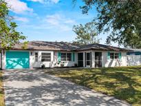 Charming single-story home featuring a bright turquoise garage door, complemented by lush landscaping and a spacious driveway at 1212 Mango Ave, Venice, FL 34285