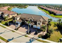 A scenic aerial view of townhouses with tile roofs, a beautiful lake, and lush landscaping, showcasing community charm at 23194 Banbury Way # 202, Venice, FL 34293