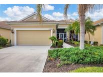 Tan house with two-car garage, landscaping, and a bird statue at 27231 Ipswich Dr, Englewood, FL 34223