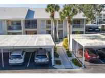 Condo building exterior with white shutters, palm trees, covered parking and staircase entry at 435 Cerromar Ln # 328, Venice, FL 34293