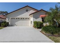 Charming home with a well-manicured lawn, white stucco, and a clean driveway leading to the two car garage at 4951 Summertree Rd, Venice, FL 34293