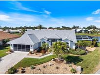 An eye-level view of a home with a white exterior, lush landscaping, and an adjacent screened-in pool and waterfront area at 734 Sugarwood Way, Venice, FL 34292