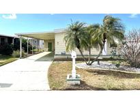 Charming single Gathering home featuring a welcoming front yard, palm trees, and covered parking at 105 Lakeview Dr, North Port, FL 34287