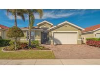 Charming single-story home featuring a two-car garage, lush landscaping, and a brick paved driveway at 11666 Parrotfish St, Venice, FL 34292