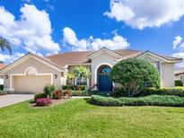 Charming one-story home with a well-manicured lawn, lush landscaping, and a covered entryway at 1241 Reserve Dr, Venice, FL 34285