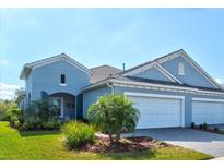 Charming blue home featuring a well-maintained lawn and two-car garage at 12505 Palatka Dr, Venice, FL 34293