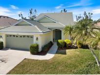 Charming single-story home featuring a light yellow exterior, well-manicured lawn, and a two-car garage with a beautiful garden at 1298 Highland Greens Dr, Venice, FL 34285