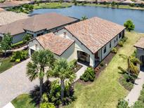 Lovely house with large lawn, brick driveway, and tile roof near a tranquil lake at 26825 Weiskopf Dr, Englewood, FL 34223