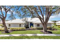 Charming single-story home with a well-manicured lawn, lush landscaping, and a pristine white tile roof at 803 Carnoustie Dr, Venice, FL 34293