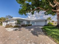 Charming single-story home featuring a brick driveway, blue shutters, a well-maintained lawn, and mature trees at 17 Brentwood Ln, Englewood, FL 34223