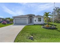 Single-story home with gray siding, attached garage, and landscaped lawn at 7057 Regina Dr, Englewood, FL 34224