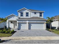 Two-story house with white exterior, two-car garage, and gray paver driveway at 9589 Vibrant Lane, Venice, FL 34292