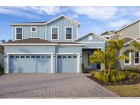 Two-story light blue house with a three-car garage and a landscaped front yard at 1005 Signet, Apollo Beach, FL 33572