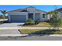 One-story home with gray siding, two-car garage, and landscaped yard at 9572 Vibrant Lane, Venice, FL 34292