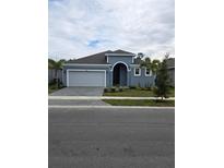 Newly constructed home with gray exterior, two-car garage, and landscaped yard at 9584 Vibrant Lane, Venice, FL 34292