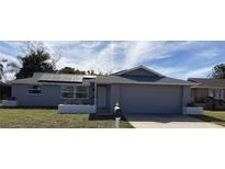 Gray house with solar panels, landscaped yard, and attached garage at 7524 Oakshire Dr, Port Richey, FL 34668