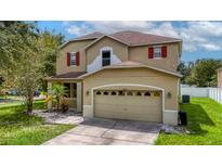 Two-story house with tan exterior, red accents, and a two-car garage at 10617 Bamboo Rod Cir, Riverview, FL 33569