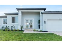 New construction home with gray exterior, white garage door, and landscaped lawn at 10071 Kingsville Dr, Port Charlotte, FL 33981