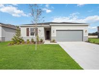 Single-story home with gray garage door and well-manicured lawn at 37513 Williamette Way, Zephyrhills, FL 33540