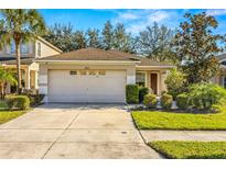 Single-story house with a two-car garage and well-maintained landscaping at 7851 Tuscany Woods Dr, Tampa, FL 33647