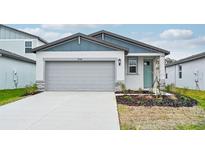 One-story home with gray siding, gray garage door, and landscaping at 14048 Crutchfield Ct, Parrish, FL 34219