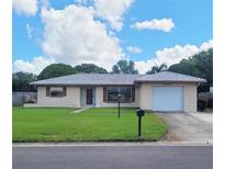 Ranch style home with a well-manicured lawn and attached garage at 2587 Blackwood Cir, Clearwater, FL 33763