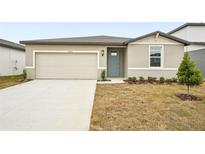 Tan house with a two-car garage and teal front door at 31650 Malbec Dr, Brooksville, FL 34602