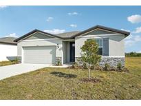 One-story house with gray siding, stone accents, and a two-car garage at 31703 Wild Grape Ln, Brooksville, FL 34602