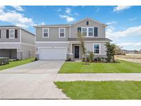Two-story house with gray siding, green shutters, and a two-car garage at 37598 Mackenzie Dr, Zephyrhills, FL 33540