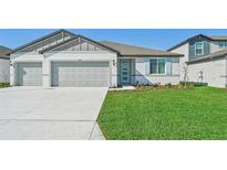 Newly constructed home with a two-car garage and well-manicured lawn at 13851 Richland Gulf Cir, Parrish, FL 34219