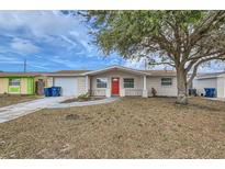 Tan house with red door, driveway, and landscaping at 3531 Oxford Dr, Holiday, FL 34691
