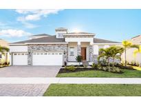Beautiful single-Gathering home featuring a well-manicured lawn, a three-car garage, and stone veneer accents at 1078 Signet Dr, Apollo Beach, FL 33572