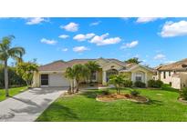 Single-story house with a two-car garage and palm trees in the front yard at 15392 Taurus Cir, Port Charlotte, FL 33981
