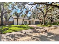 A charming single-story home with a gray garage door and a beautifully landscaped yard at 1911 Rain Forest Trl, Sarasota, FL 34240