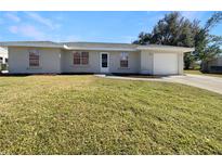 Newly renovated single-story home with a spacious lawn and attached garage at 3944 Nekoosa St, North Port, FL 34287