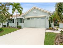 Light green house with a two-car garage and landscaped lawn at 7313 Emma Rd, Bradenton, FL 34209