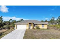 House exterior featuring a yellow single-story home with a two-car garage and driveway at 7864 Jayman Rd, North Port, FL 34291