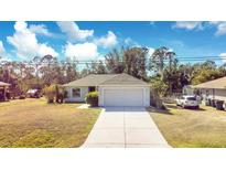 Single-story home with a driveway and a grassy lawn at 2315 Snowflake Ln, North Port, FL 34286