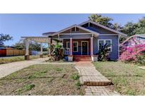 Charming bungalow with a gray exterior, porch, and landscaped yard at 7108 N 10Th St, Tampa, FL 33604