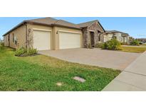 Two-car garage, stone accents, and landscaped lawn at 8796 Little Bluestem Dr, Land O Lakes, FL 34637