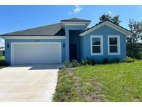 Newly constructed light blue house with a two-car garage and manicured lawn at 7340 Bass St, Englewood, FL 34224