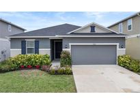 Curb appeal abounds in this charming one-story home, featuring a gray exterior and lush landscaping at 9474 Sanders Park Pl, Seffner, FL 33584