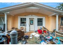 Front view of a single-story house needing repairs, with cluttered porch at 4119 Beacon Square Dr, Holiday, FL 34691