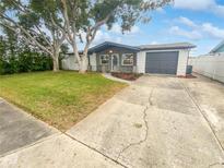 Updated home exterior boasts a gray and white color scheme, landscaping, and a spacious driveway at 1414 Wickham Ln, Holiday, FL 34691